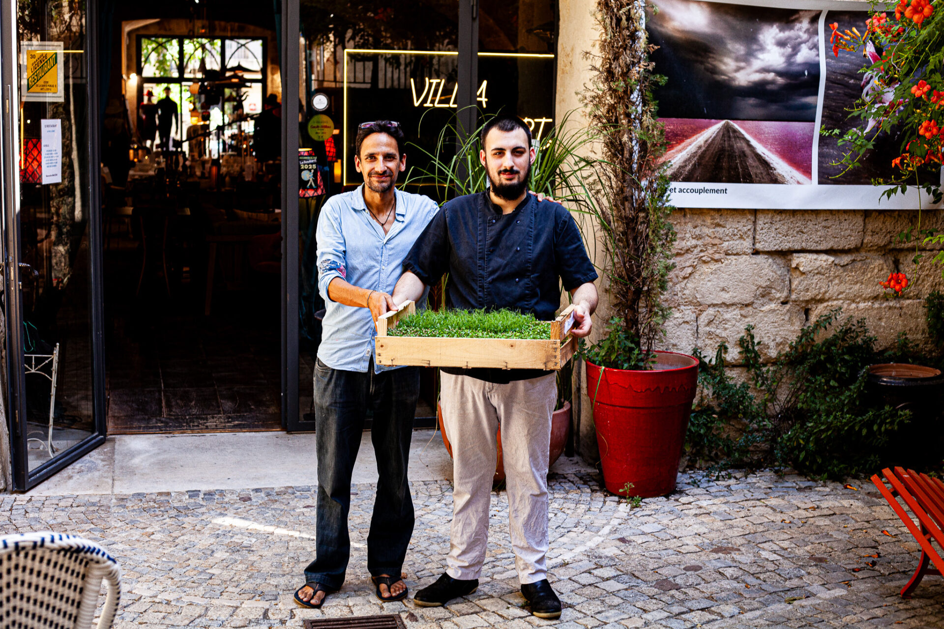 Patrick Vibert avec Mathéo devant Villa Curti, présentant une barquette de micropousses vivantes