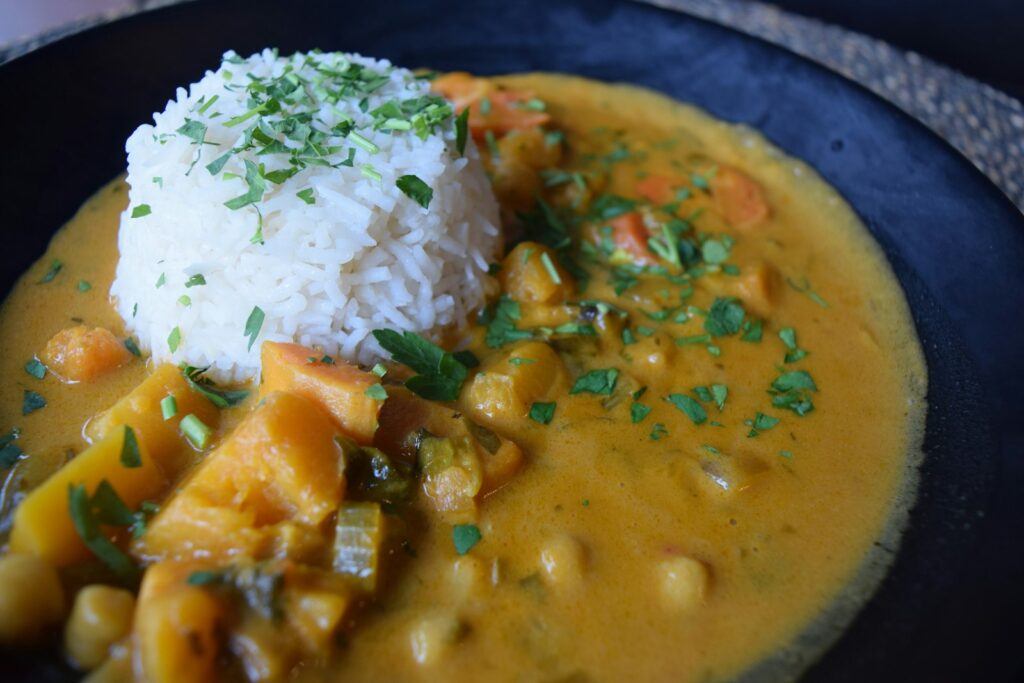 Bol de curry végétal aux légumes servi avec du riz et des herbes fraîches